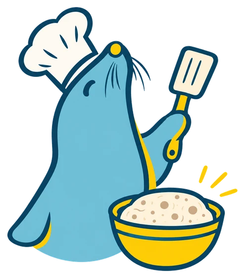 La foca con gorro de cocinero, una espátula y un bol de masa